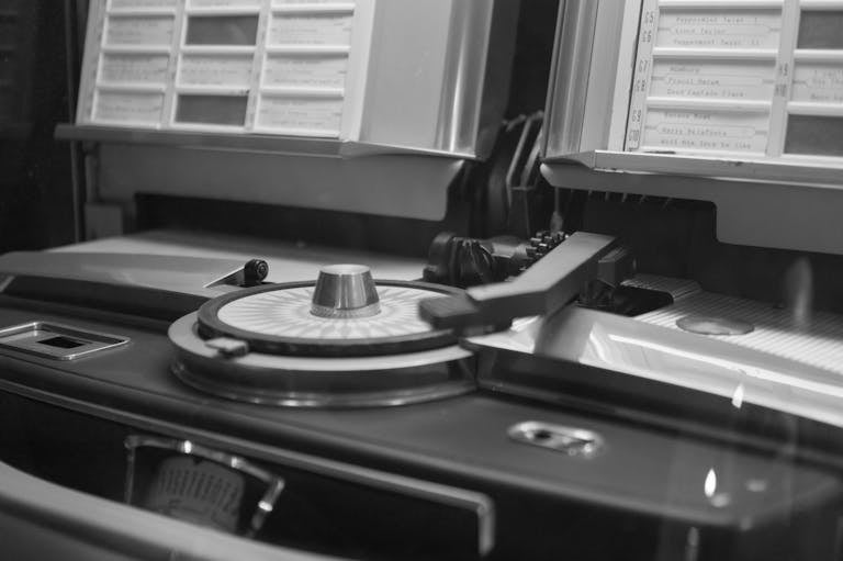 Black and white close-up of a vintage jukebox turntable with song list.