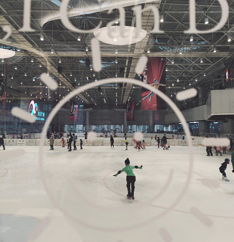 People ice skating at an indoor rink in Beijing with modern architectural design.